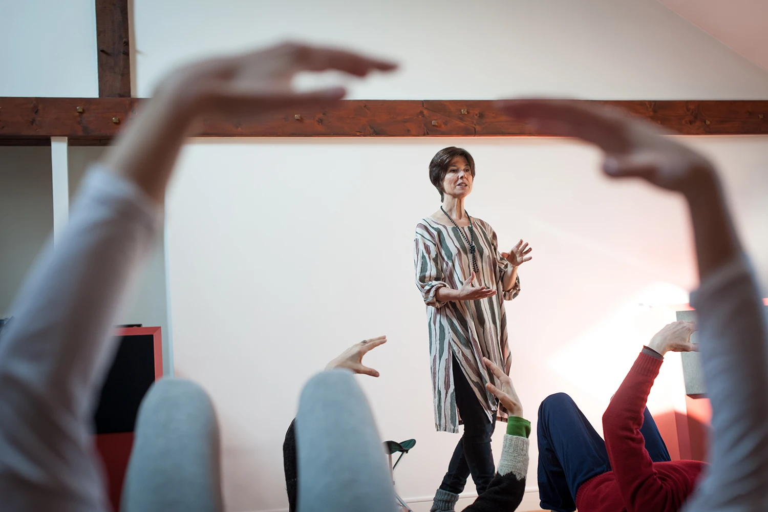 Sabine Chambon-Marquis explique un mouvement lors d'un atelier collectif, participants aux mains levées au premier plan